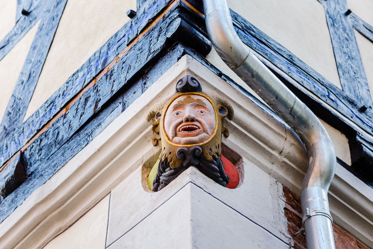 Geschnitzte, bunt bemalte Fratze an der Hausecke